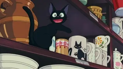 Black cat sitting on a shelf surrounded by cups