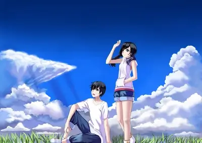 Boy and girl sitting in a grassy field under a bright blue sky