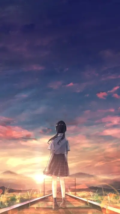 Girl gazes into vibrant sunset, standing on railroad tracks with mountains backdrop.
