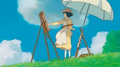 Girl painting on canvas under umbrella on sunny grassy hill