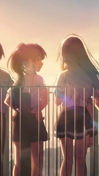 Girls stand behind a fence at sunset