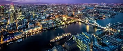 Night aerial view of London, showcasing the iconic Tower Bridge and illuminated cityscape