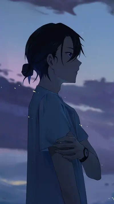 Pensive young man with a bun standing against a dreamy evening sky
