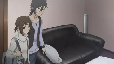 Two people standing in a room next to a black leather couch
