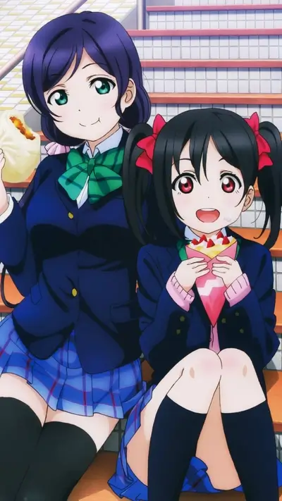 Two schoolgirls sitting on stairs, one eating a bun, the other a crepe