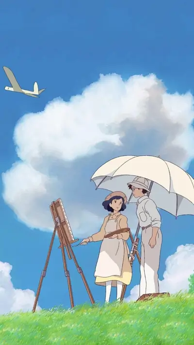 Young couple painting under an umbrella on a grassy hill