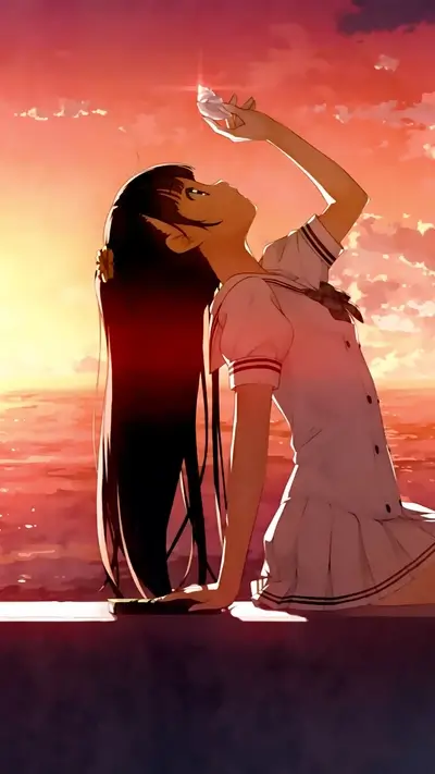 Young woman with long black hair looking at an object at sunset